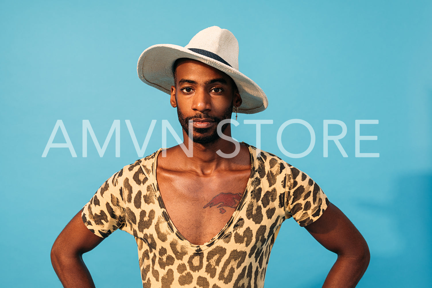 Stylish guy posing in studio against blue background looking at camera