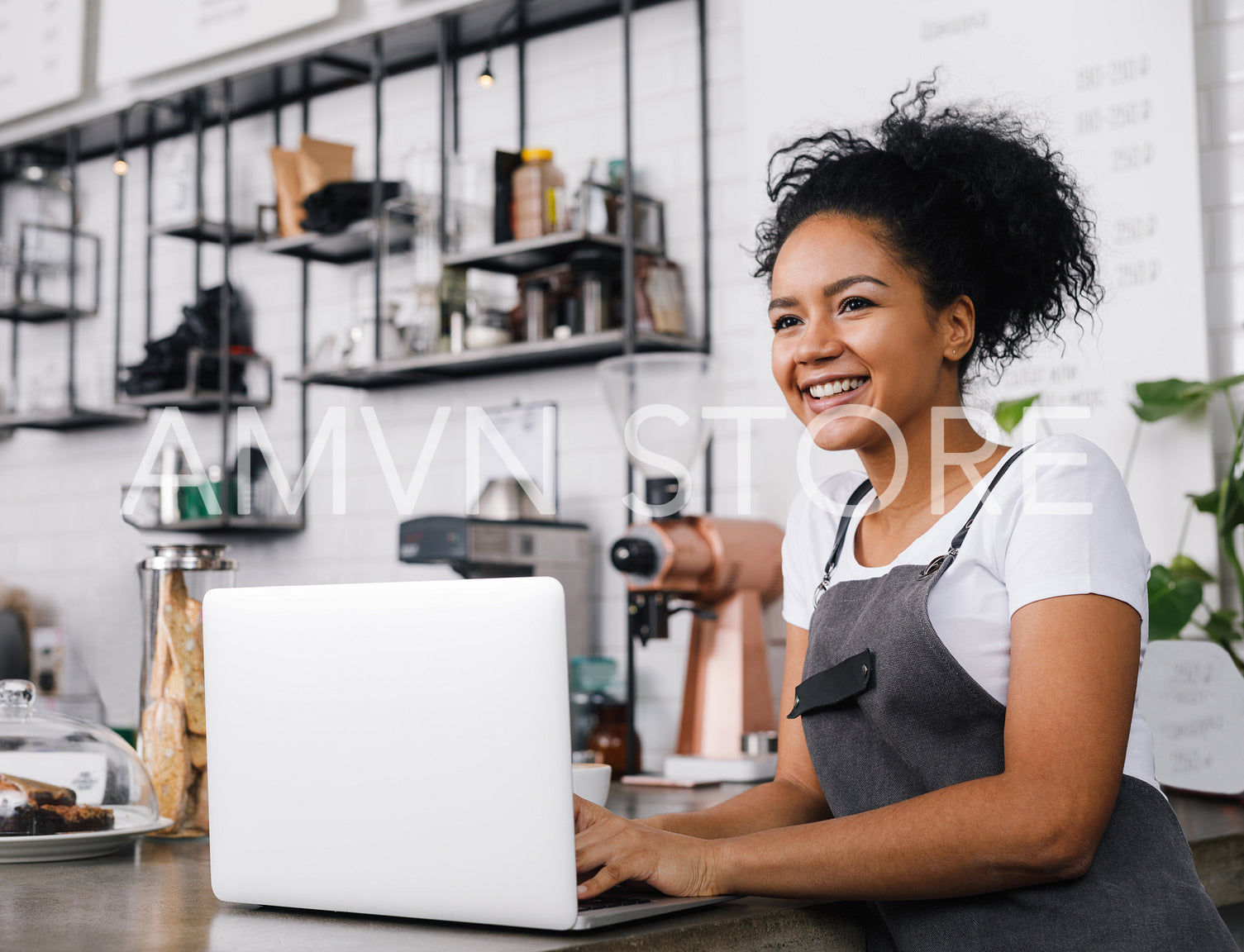 Woman in an apron using a laptop in a coffee shop	