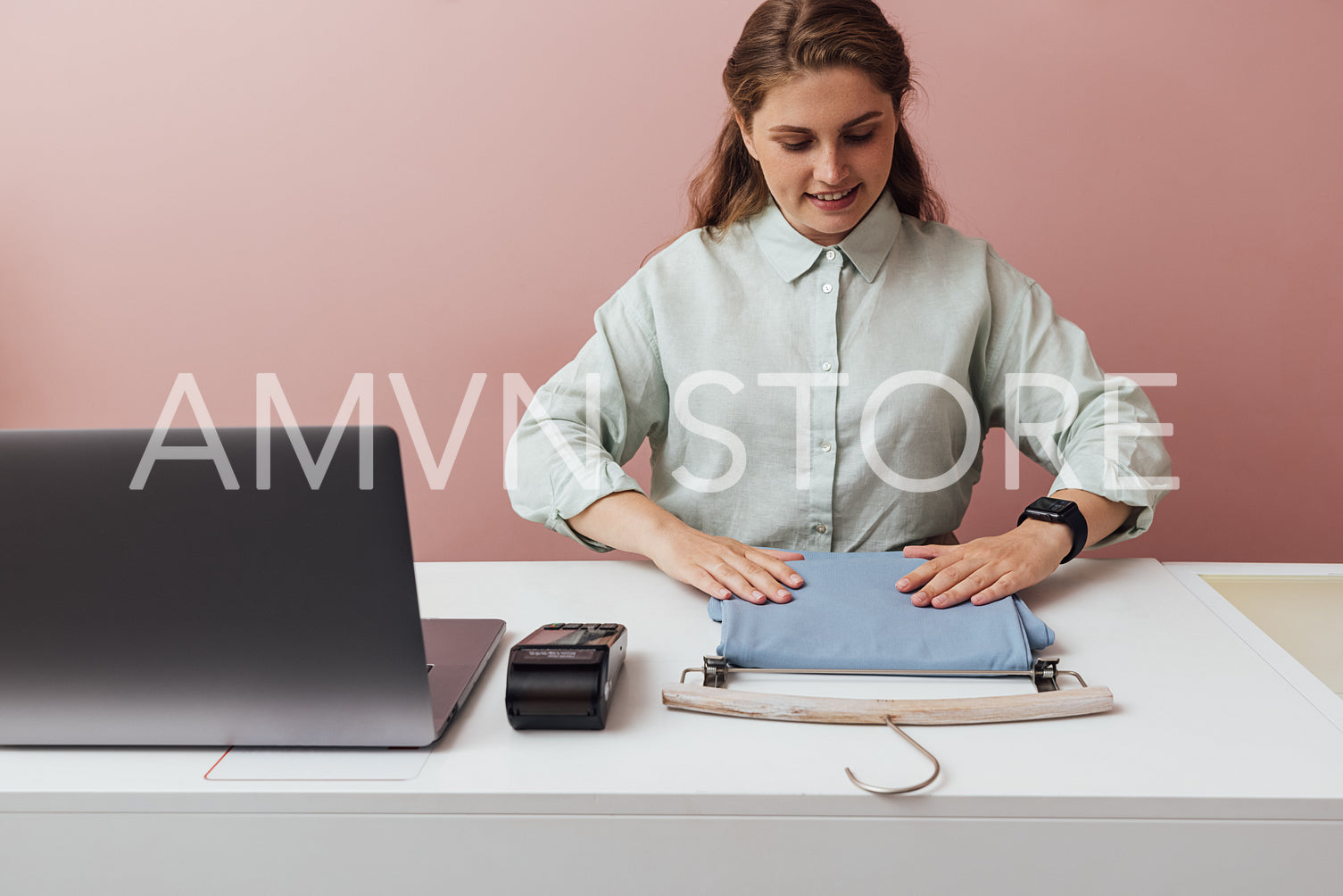 Young boutique owner straightens clothes on counter