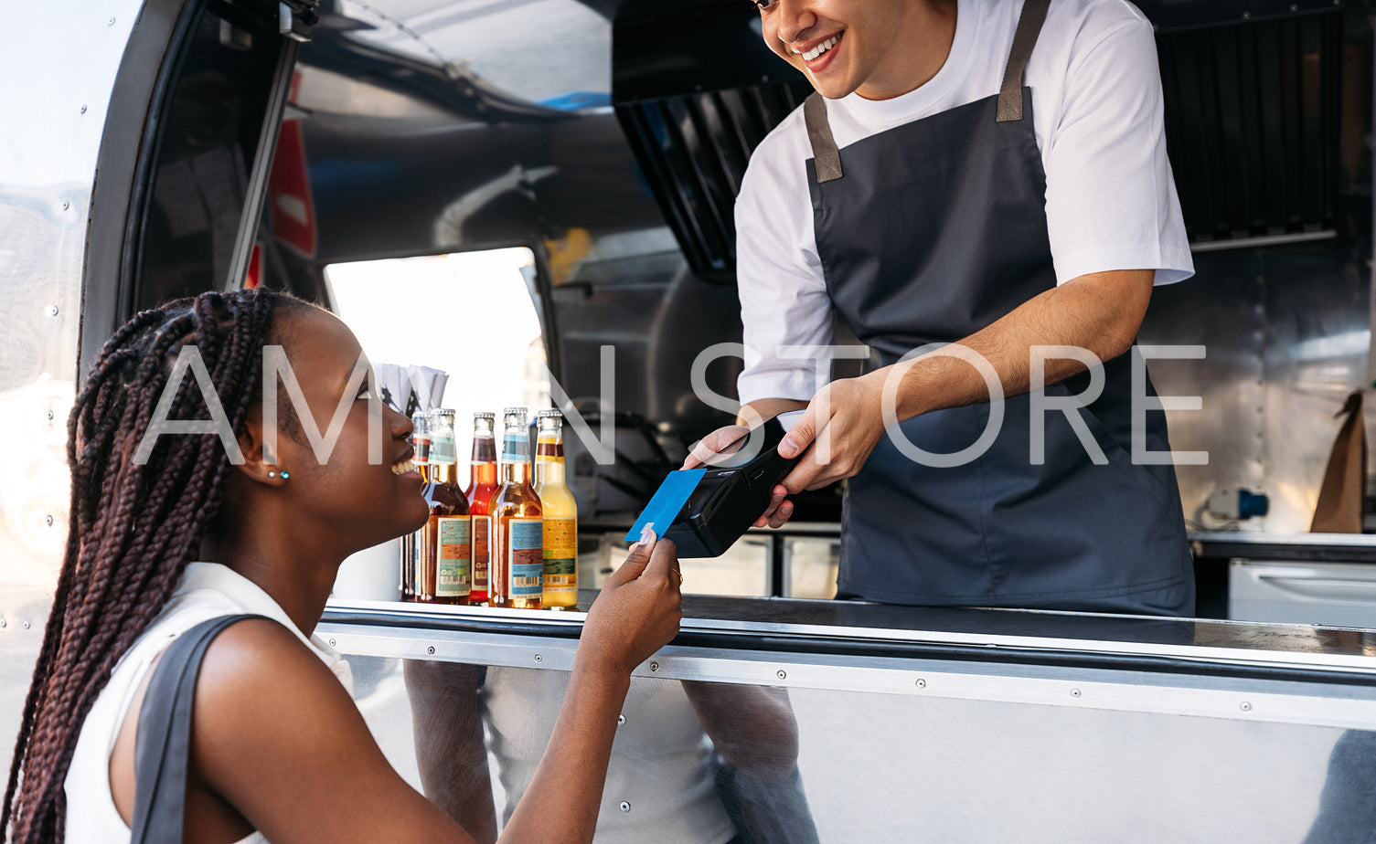 Young female paying for a meal at a food truck. Food truck owner receiving payment from a customer.