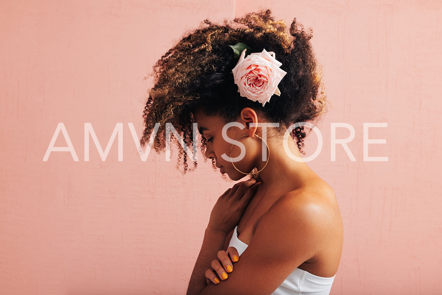 Side view of a young woman with pink flower in her curly hair