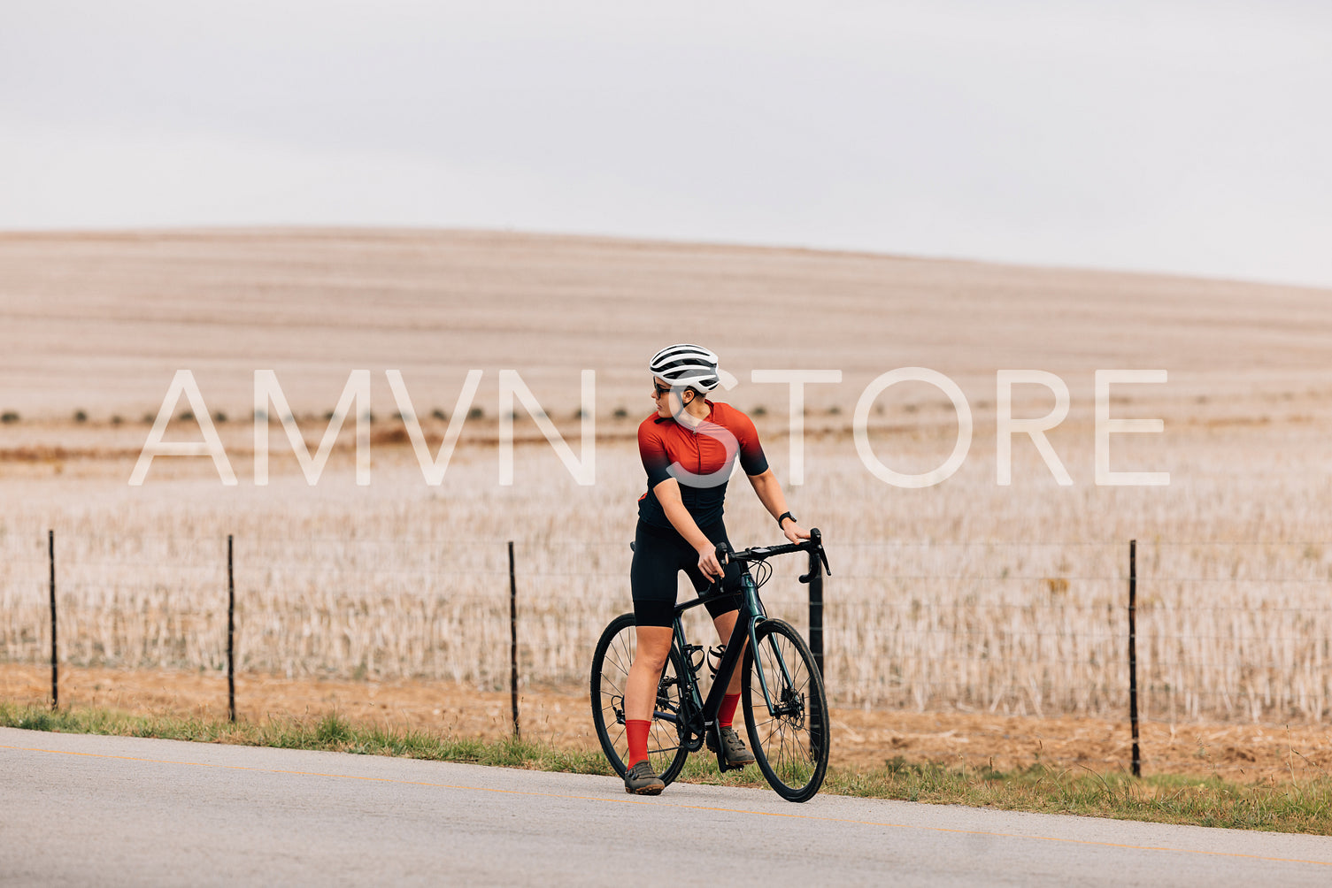 Woman cyclist standing on road with bike and looking back preparing to move