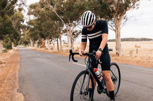 Cyclist woman in sportswear checking on board computer on her road bike during training