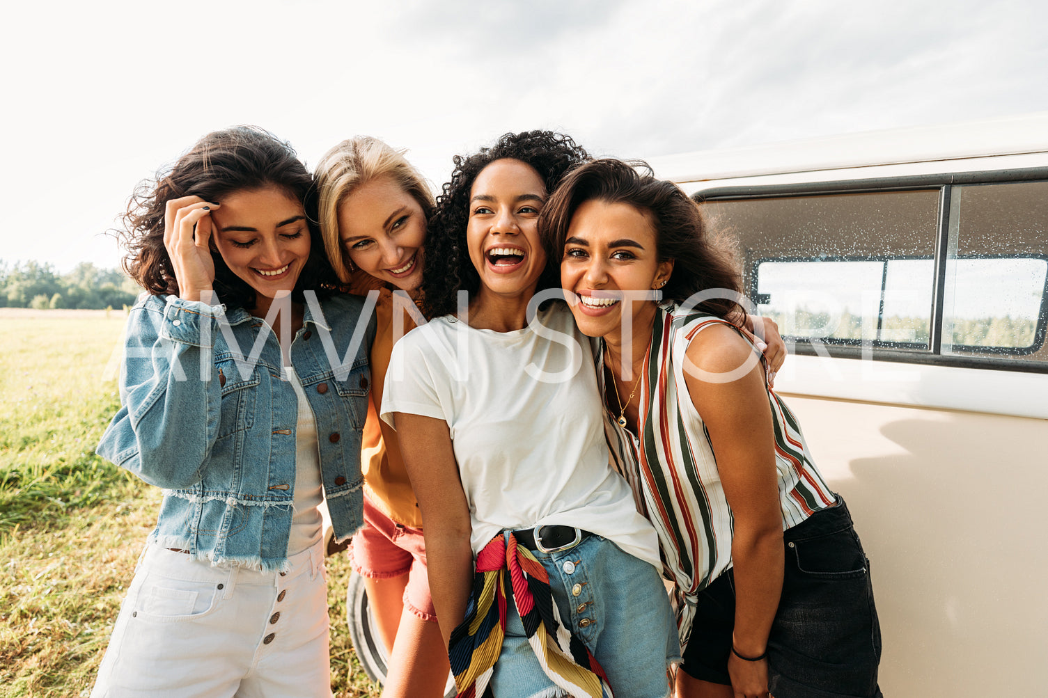 Young laughing women standing at van having good times during summer vacation