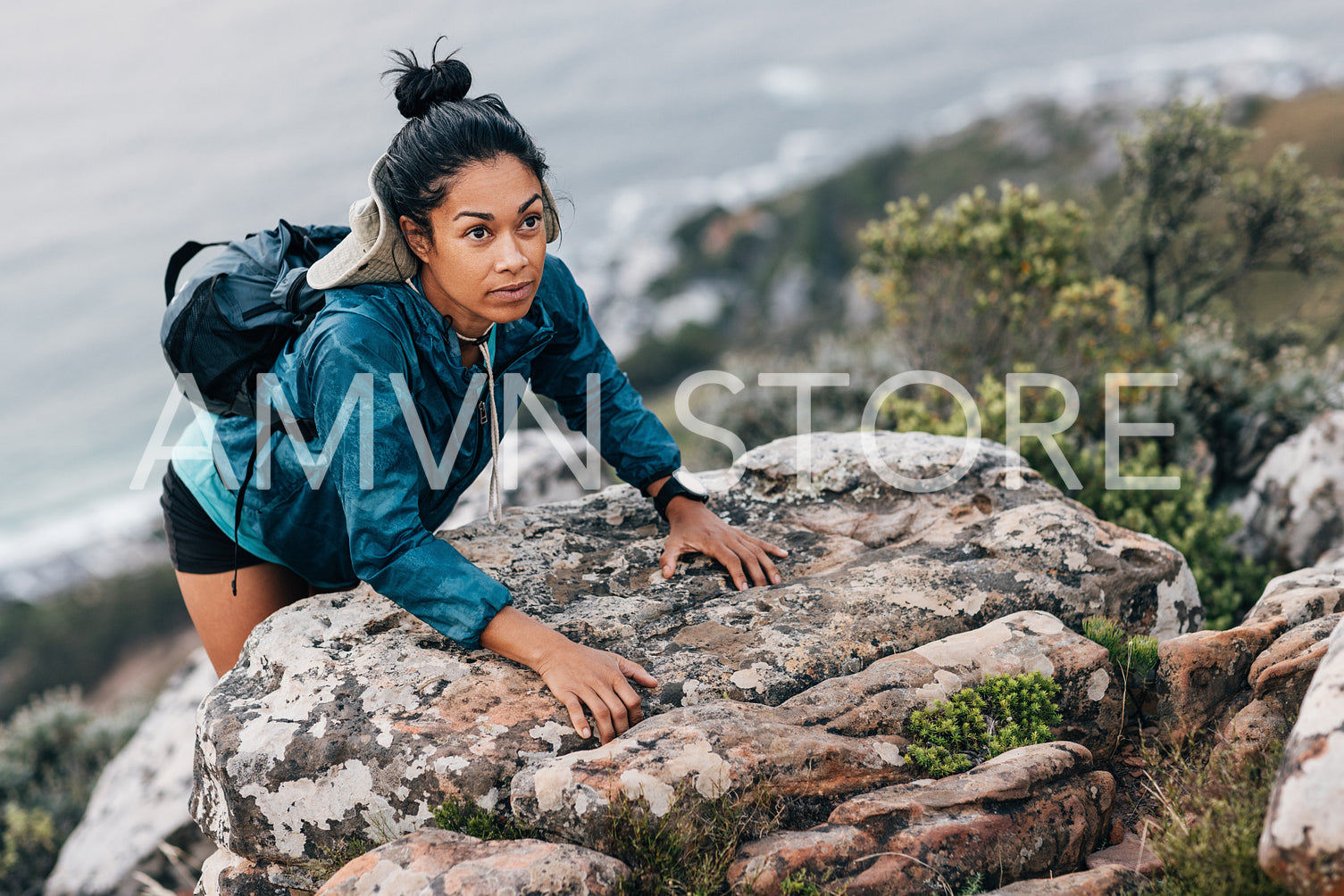 Woman hiker climbing a rock and looking away. Young female hiking over extreme terrain in mountain at the cliff.