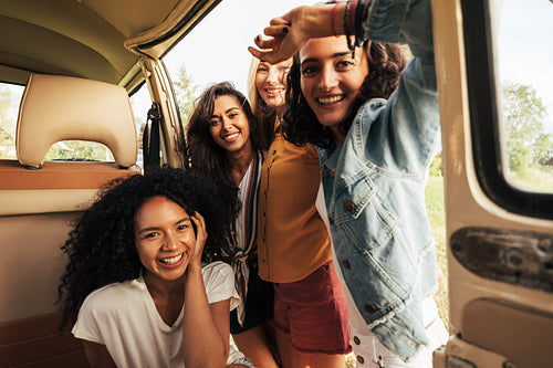 Four beautiful women looking at camera while sitting in minivan