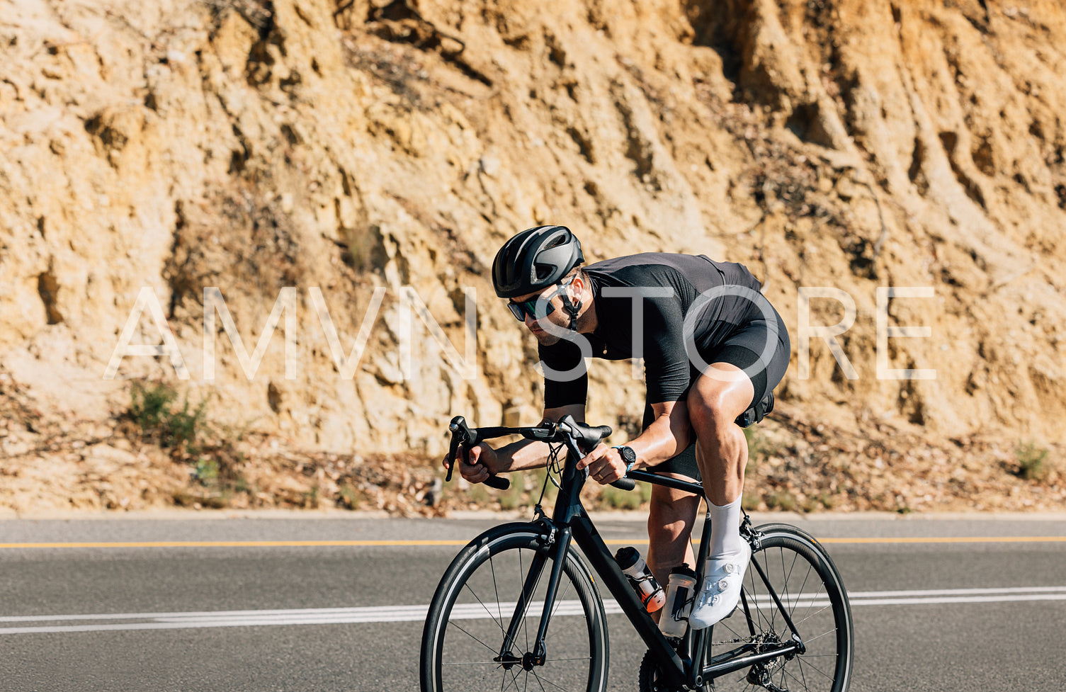 Side view of a professional male cyclist riding on a road. Strong cyclist on a countryside highway.