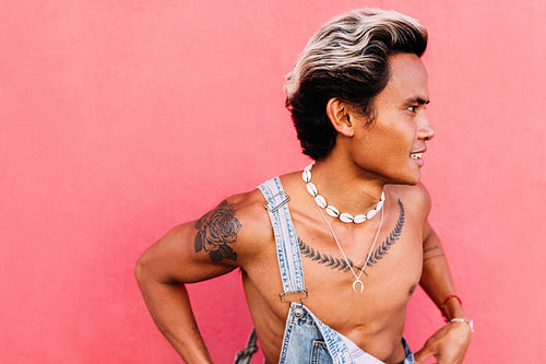 Close up of young male in denim clothing standing at pink wall l