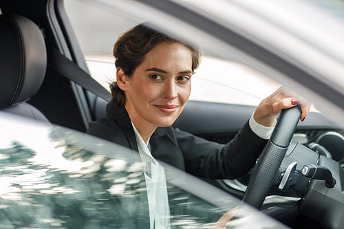 Side view of businesswoman driving car looking out of window. Portrait of a woman going to office in her car.