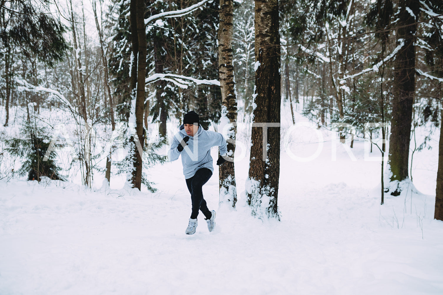 Young man running in snowy area up the hill	
