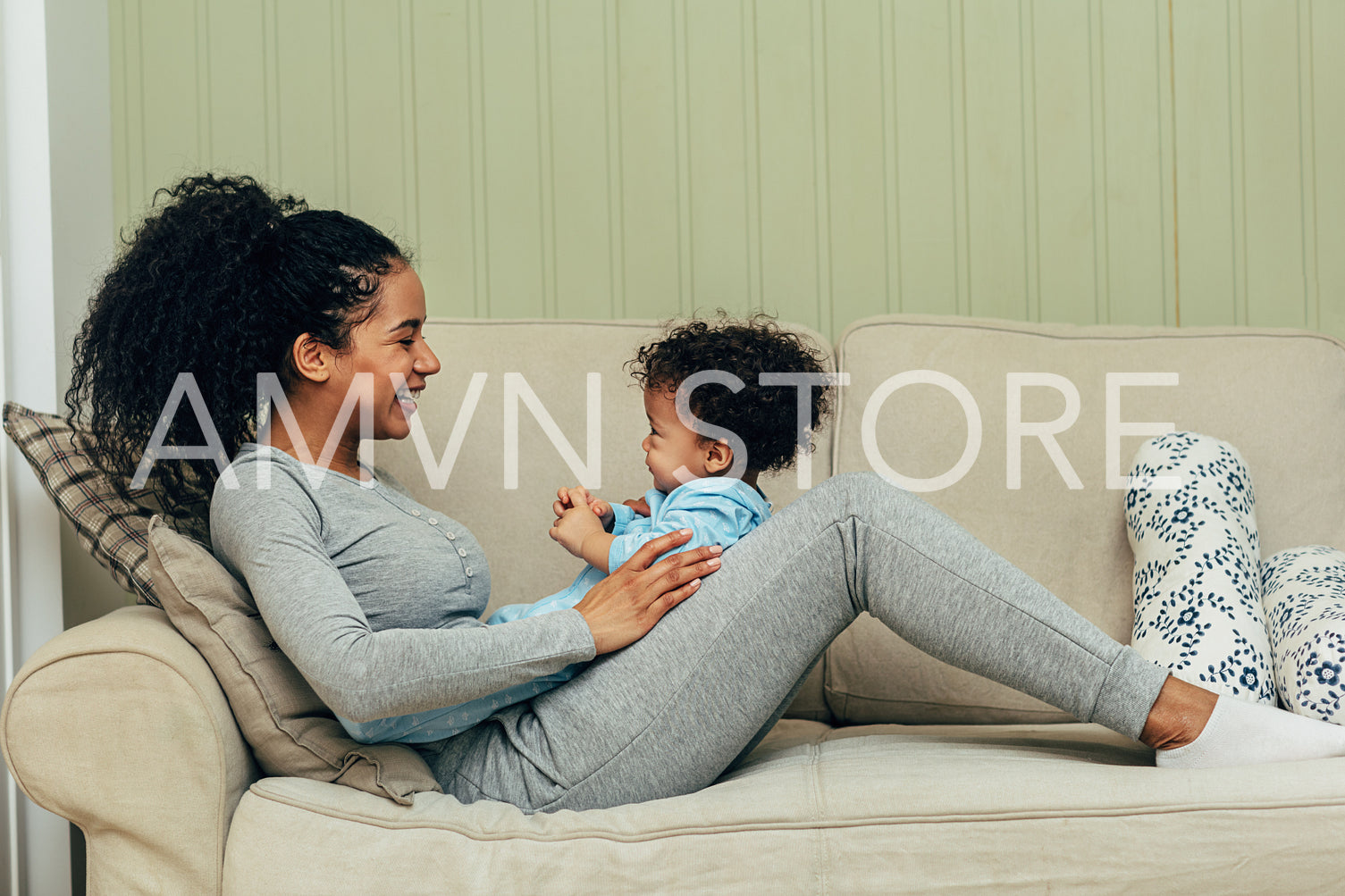 Side view of mother lying on couch and playing with her son	