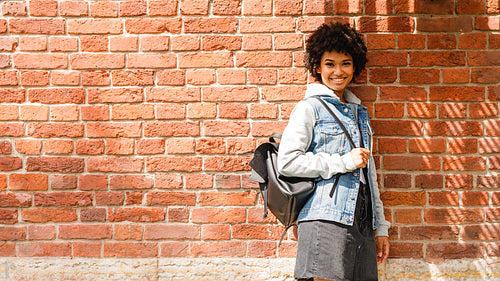 Smiling teenage girl standing at brick wall