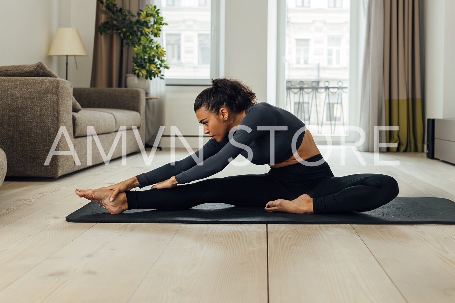 Young woman exercising in a living room. Side view of middle east female stretching legs before training.	