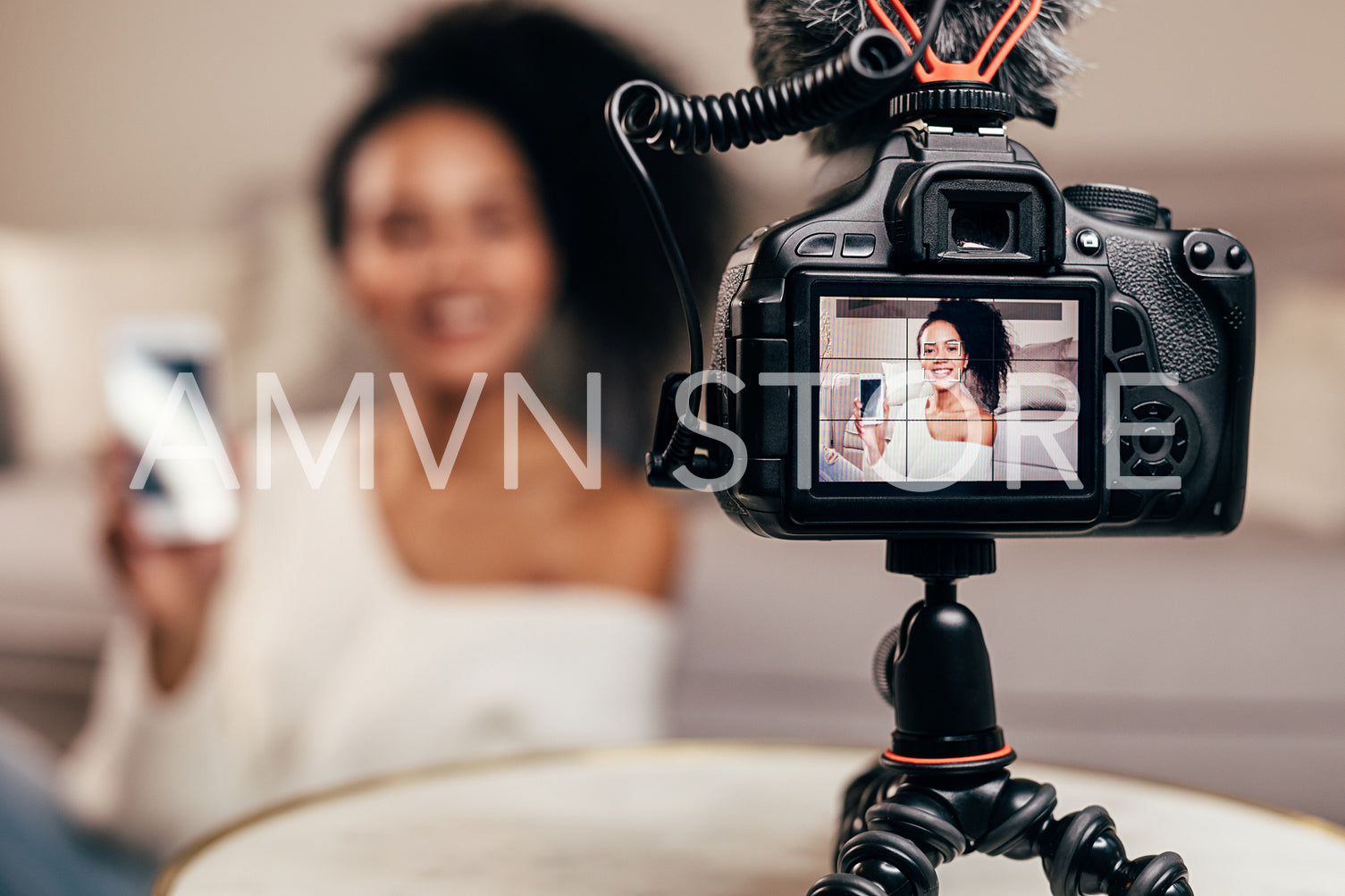 Closeup of DSLR camera screen showing a young vlogger holding a smartphone	