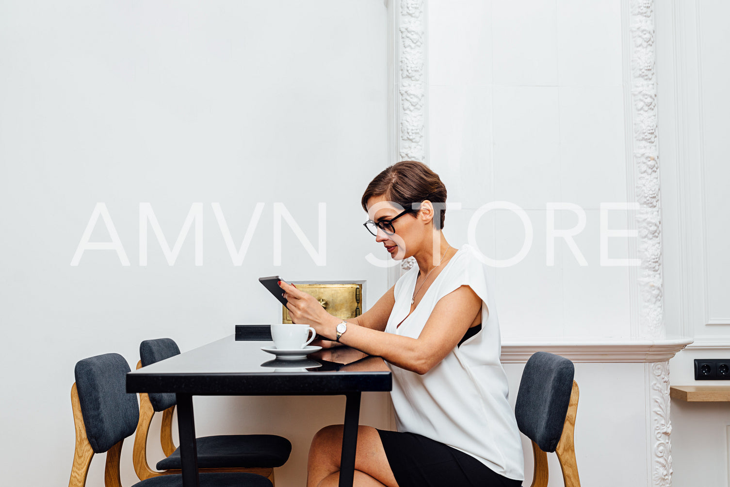 Woman sitting at table in luxury apartment and reading from digital tablet	