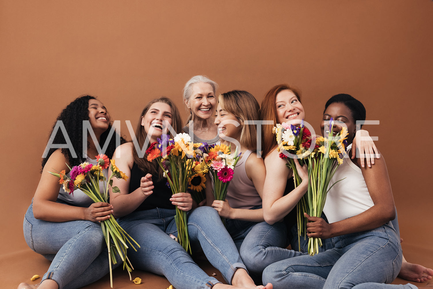 Group of multi-ethnic women sitting together in studio. Six smiling females with bouquets of flowers.