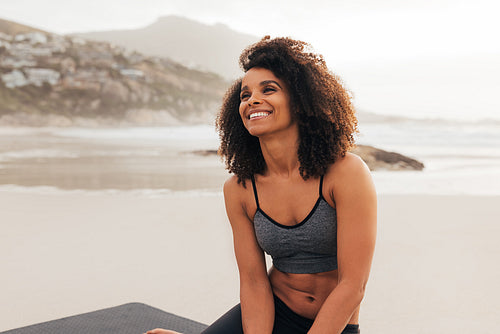 Cheerful woman relaxing after training while sitting on a beach