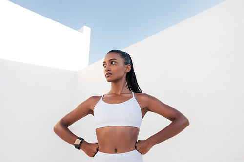 Confident slim female relaxing after workout. Fitness woman looking away with hands on hips.