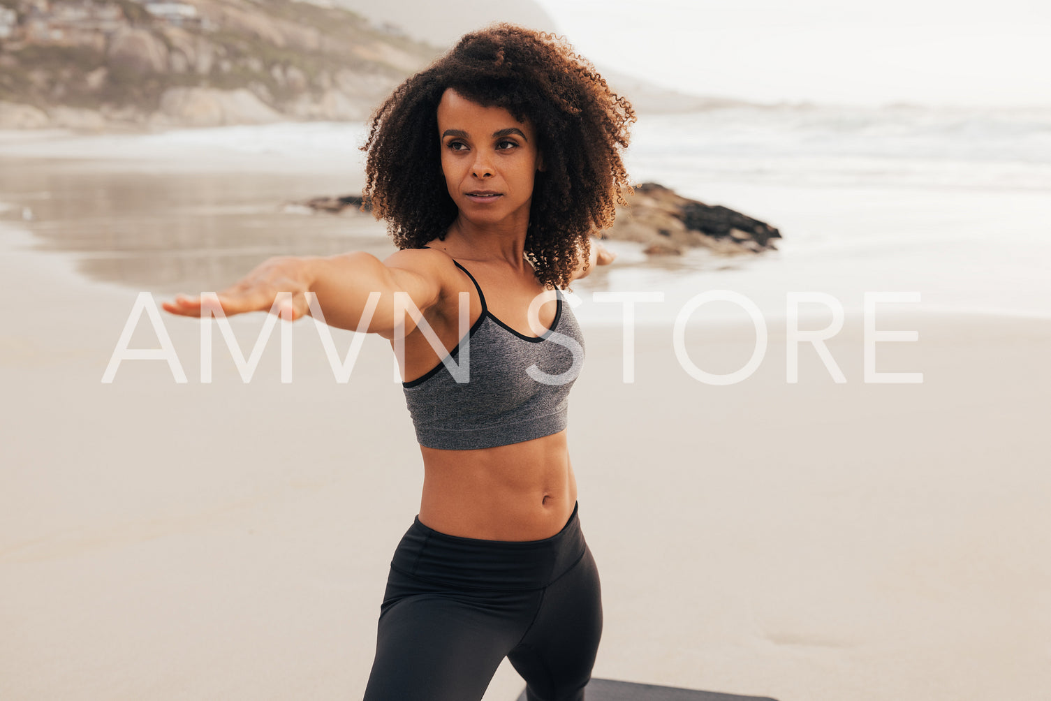 Woman in sportswear stretching her arms on a beach