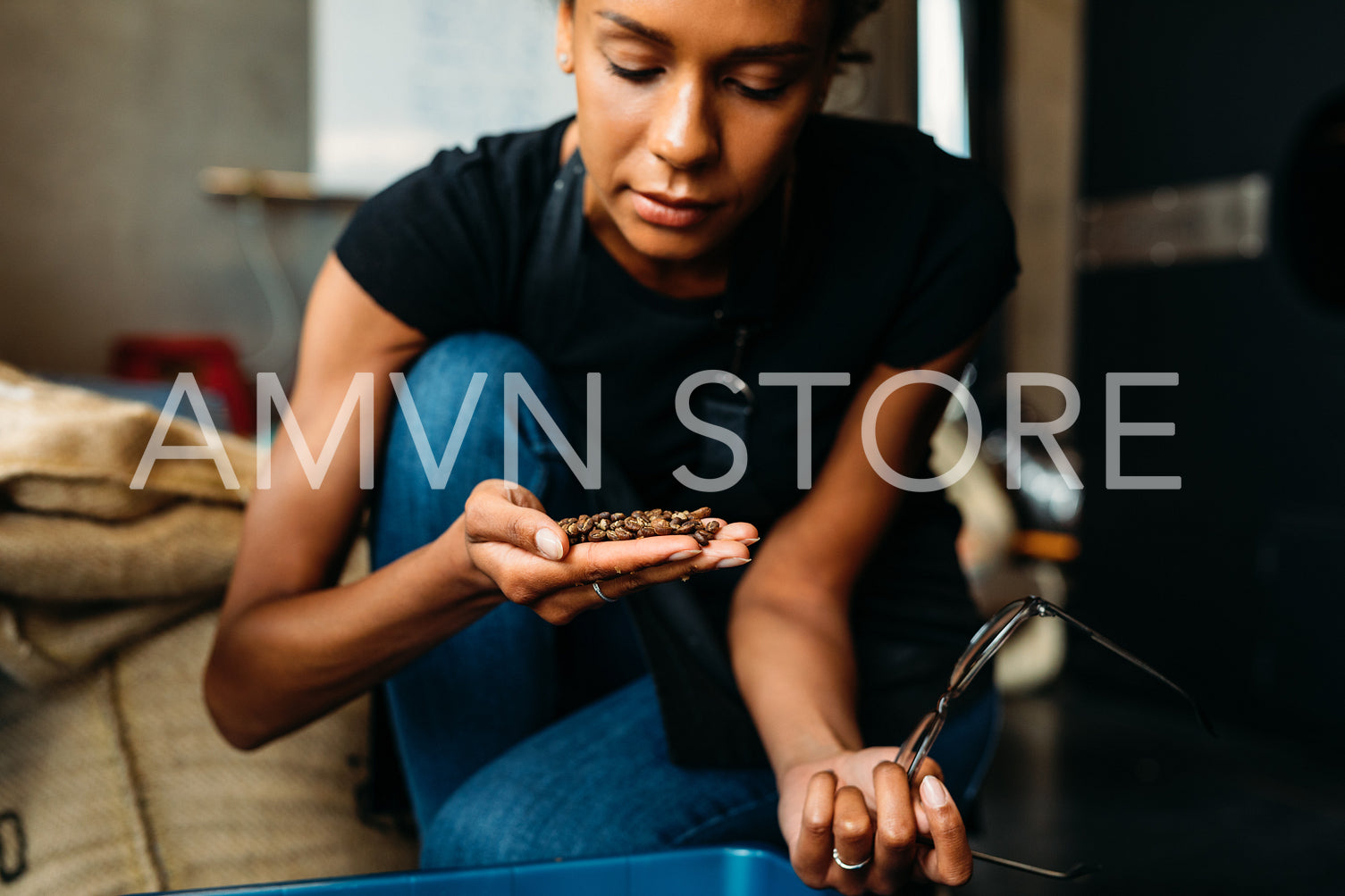 One woman sitting in her cafe, inspecting roasted coffee beans	