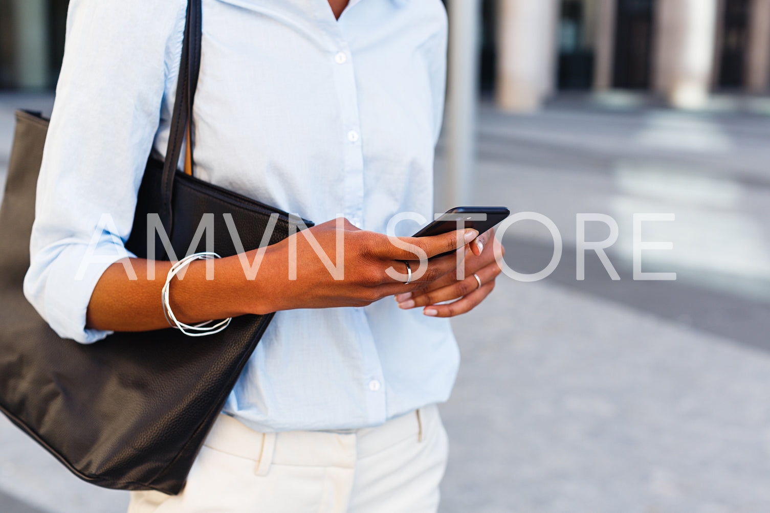 Unrecognizable businesswoman holding mobile phone in hands and texting	