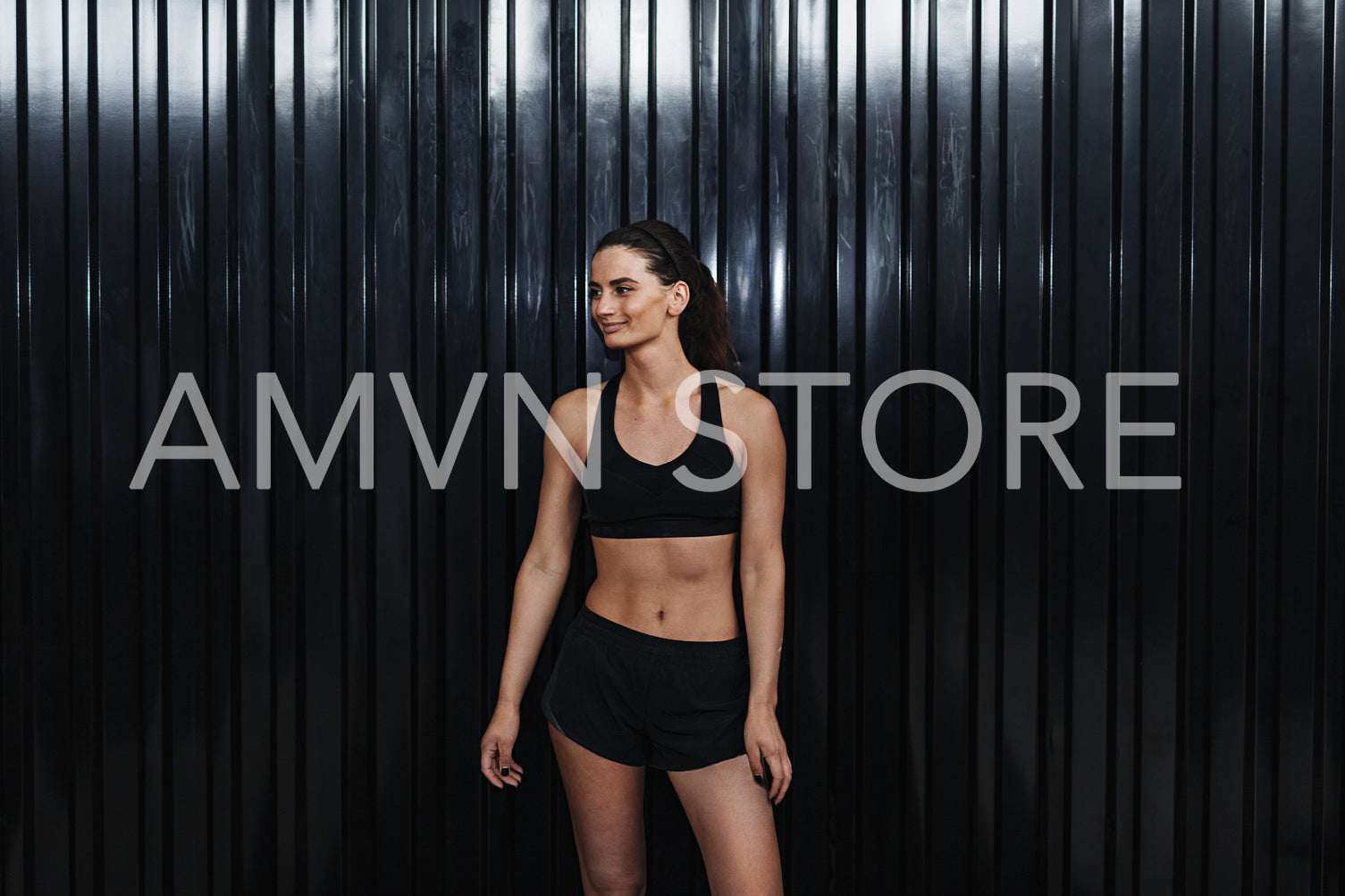 Smiling woman standing in sport club at black wall, taking a break	