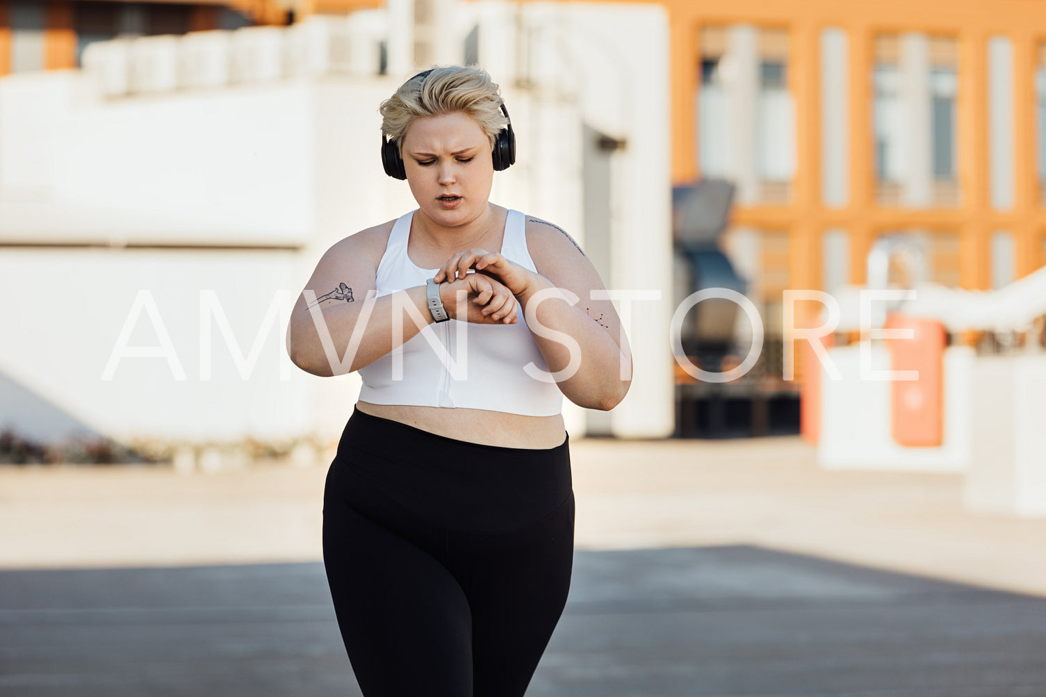 Curvy woman in sportswear checking an app on a smartwatch while running on roof	