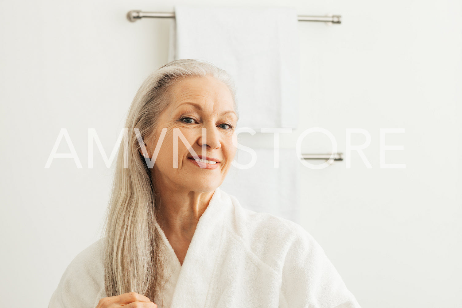 Smiling senior woman with long gray hair looking at her reflection