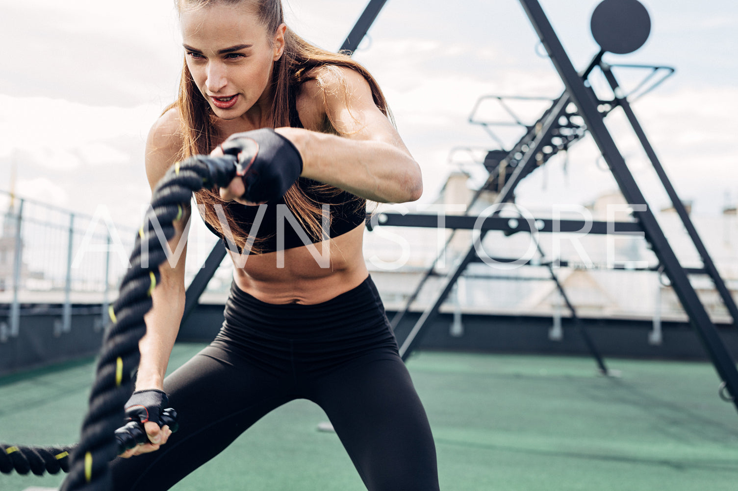 Woman doing fitness training using battle ropes on outdoors gym	
