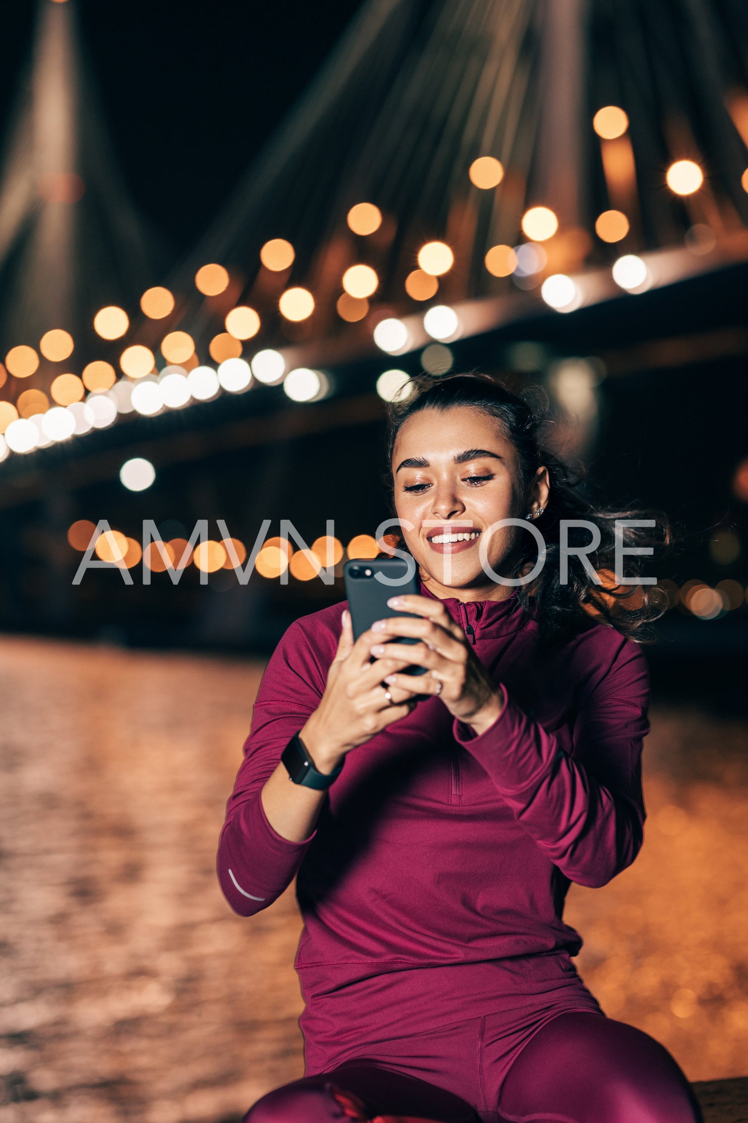 Smiling woman holding a smartphone while relaxing during training at night