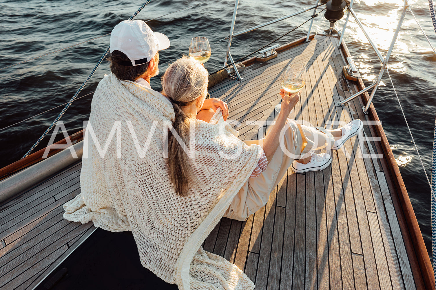 Back view of elderly couple wrapped in blanket and holding a bocals with wine	