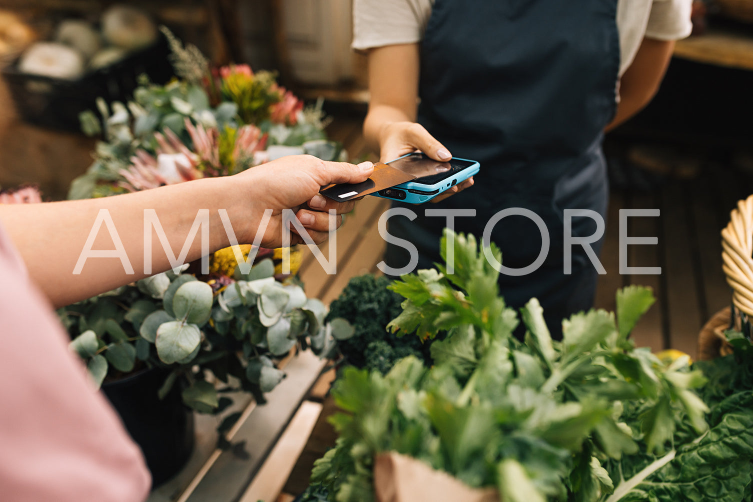 Hands of a customer and a vendor making transaction with a credit card and a pos terminal. Unrecognizable woman paying via plastic card at farmers market.