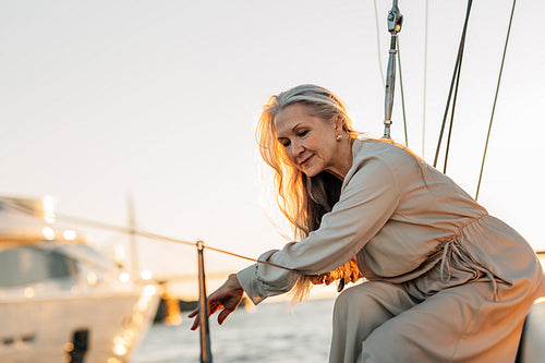 Stylish mature woman sitting on a yacht deck and looking on water