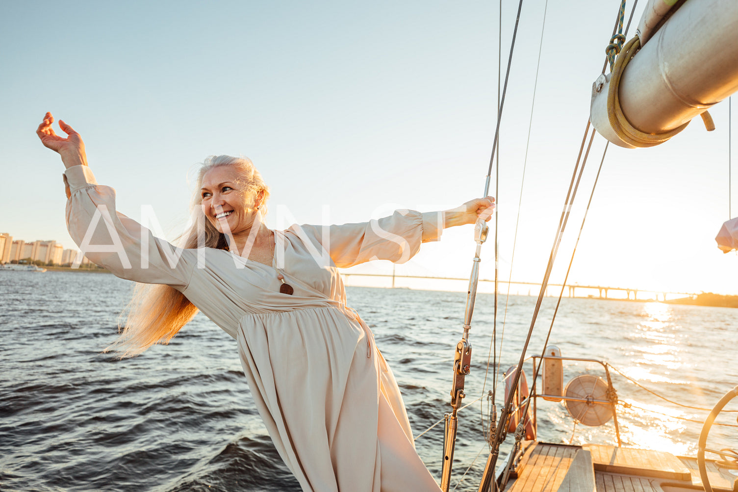 Smiling and happy mature woman enjoying sunset on a sailboat	