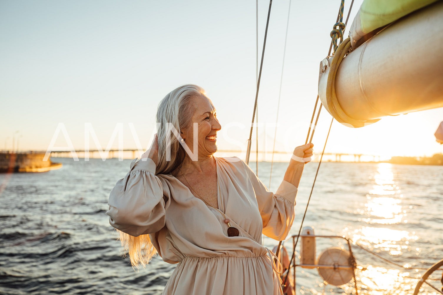 Side view of a beautiful senior woman adjusting her hair and enjoying sunset on private yacht	