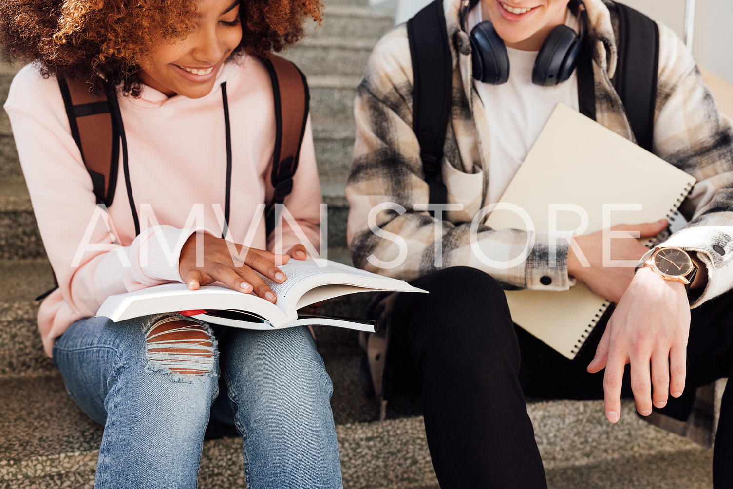 Cropped shot of two classmates sitting on stairs preparing assignments and smiling