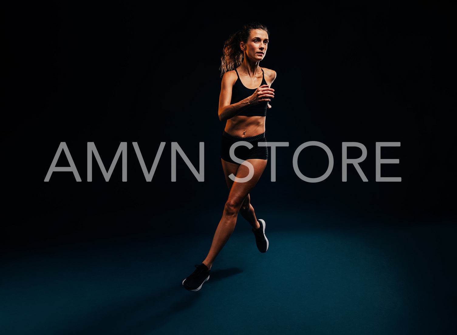 Female runner exercising on black background. Woman jogging and jumping in studio.