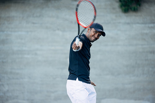 Young tennis player playing on a hard court and hitting a ball during a match