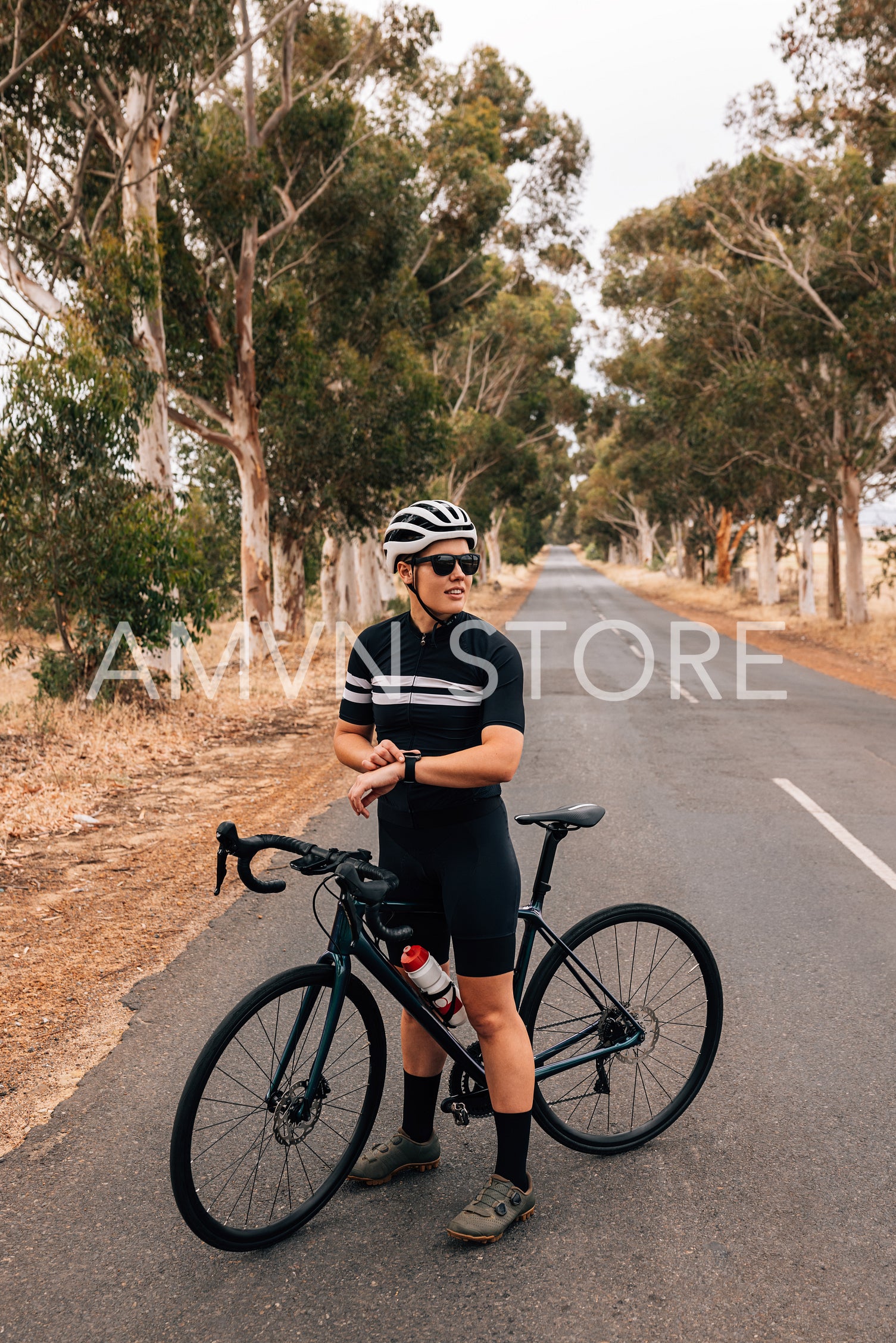 Cyclist checking smartwatch while taking a break on empty country road