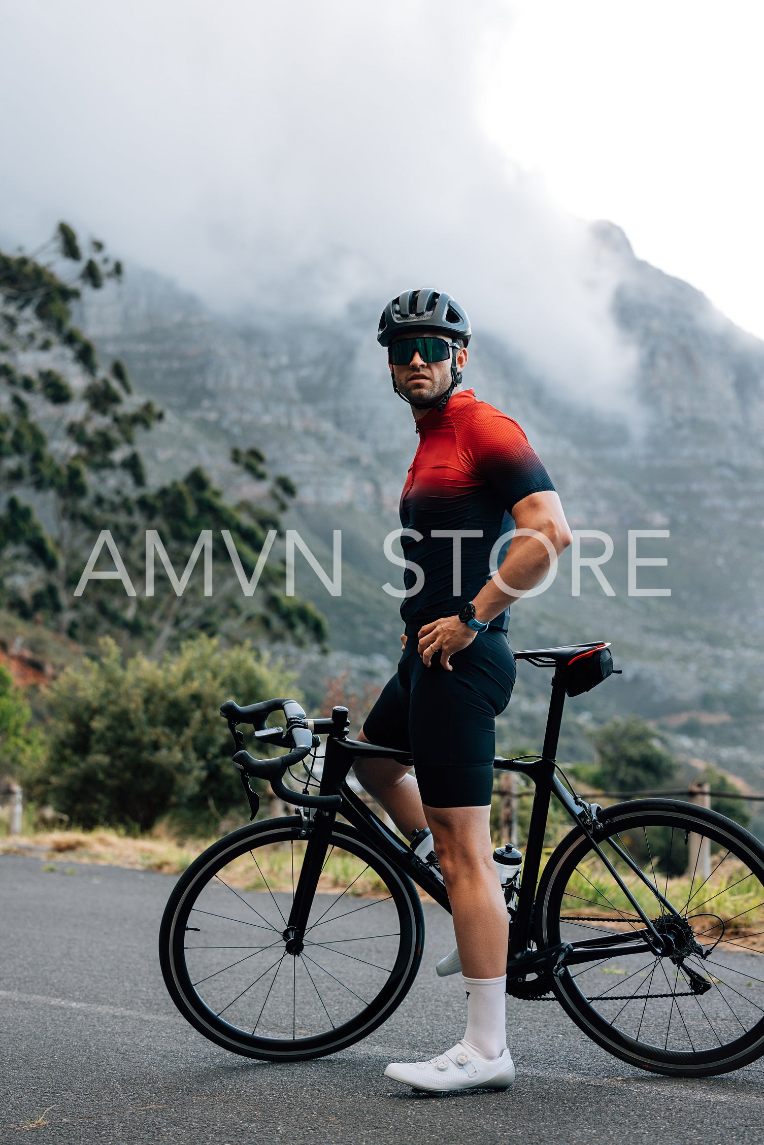 Full length of male cyclist relaxing during training. Professional cyclist standing against a mountain and looking away.