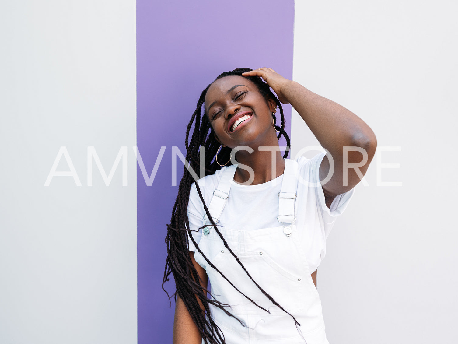 Young woman with braids having fun outdoors. Happy female with closed eyes wearing white casual clothes.