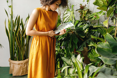 Young woman holding a book and observe a plant in workshop