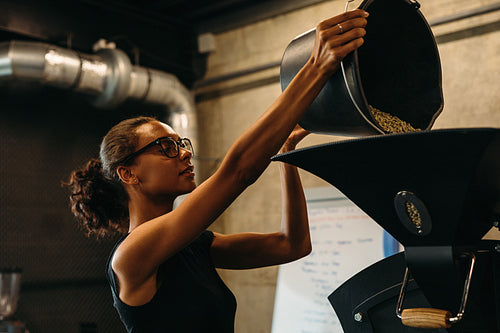 Woman putting coffee beans in the coffee roasting machine