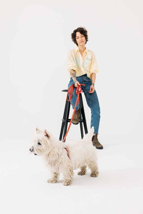 Woman in casual clothes with her dog in studio against white bac