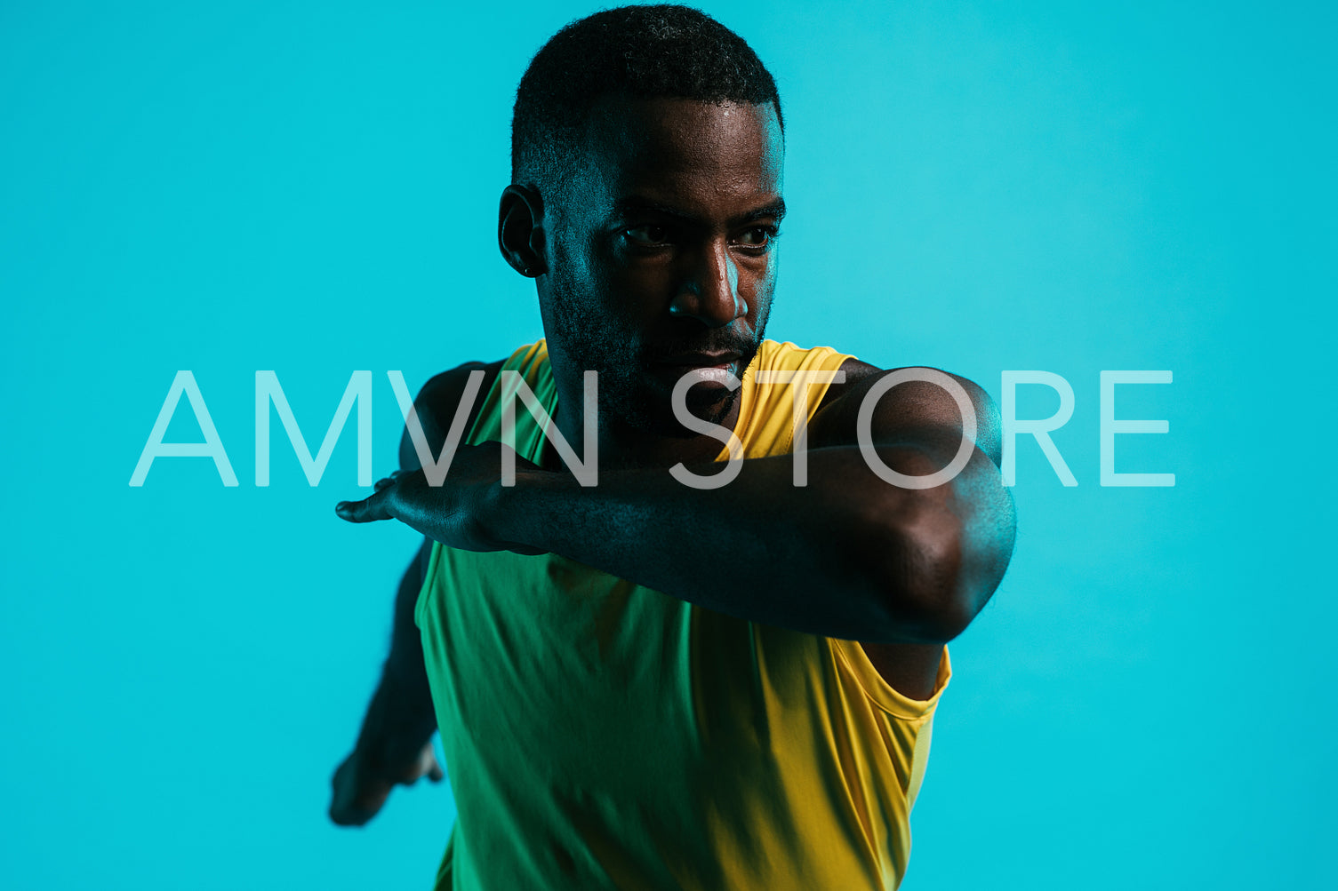 Close up of male athlete stretching arms and body in studio over blue background