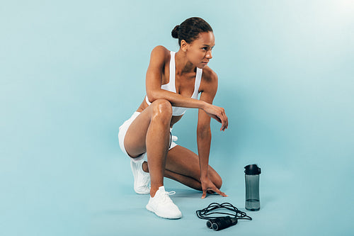 Young muscular sports woman taking a break during training in studio