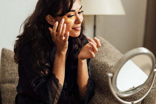 Young woman doing a skincare beauty routine at home in front of a mirror