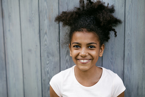 Portrait of a funny smiling girl, standing at wall outdoors