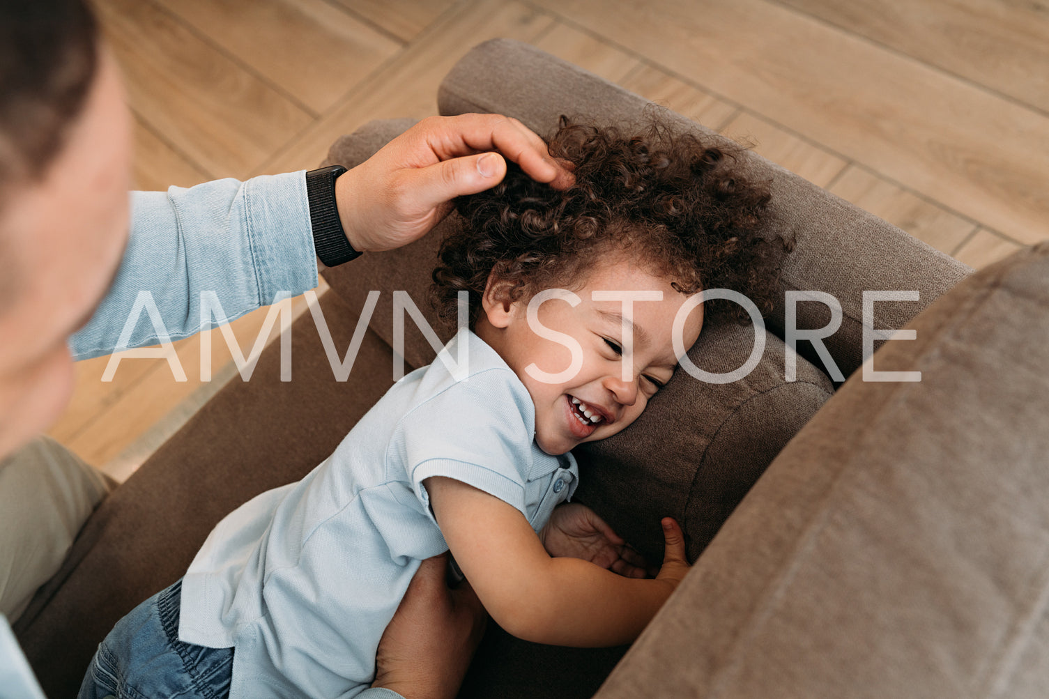 Father and his young son playing on the sofa