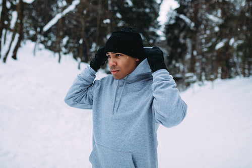 Sportsman standing in winter forest, holding a hood